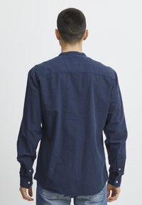 Navyblauwe lange mouwen shirt met een knoopsluiting kraag, achterpand en een afgeronde zoom. Voorzien van manchetknopen en een gestructureerde stof. Stijlvol casual ontwerp.