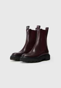 Burgundy bőr Chelsea csizmák elasztikus oldalsó panelekkel, húzófüllel, strapabíró fekete talppal és texturált varrással a szélén rendelkeznek.