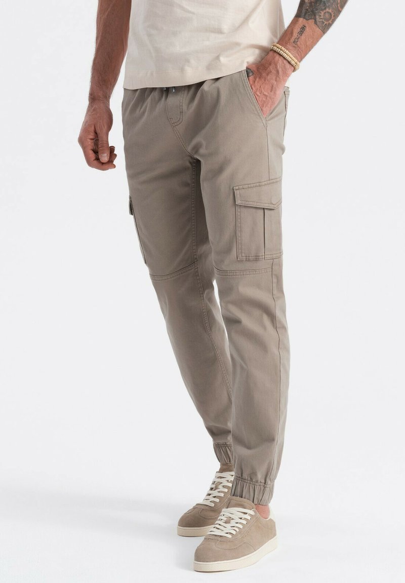 Beige cargobroek met elastische boorden, meerdere zakken en een ontspannen pasvorm. Gemaakt van lichtgewicht stof met versterkte stiksels.