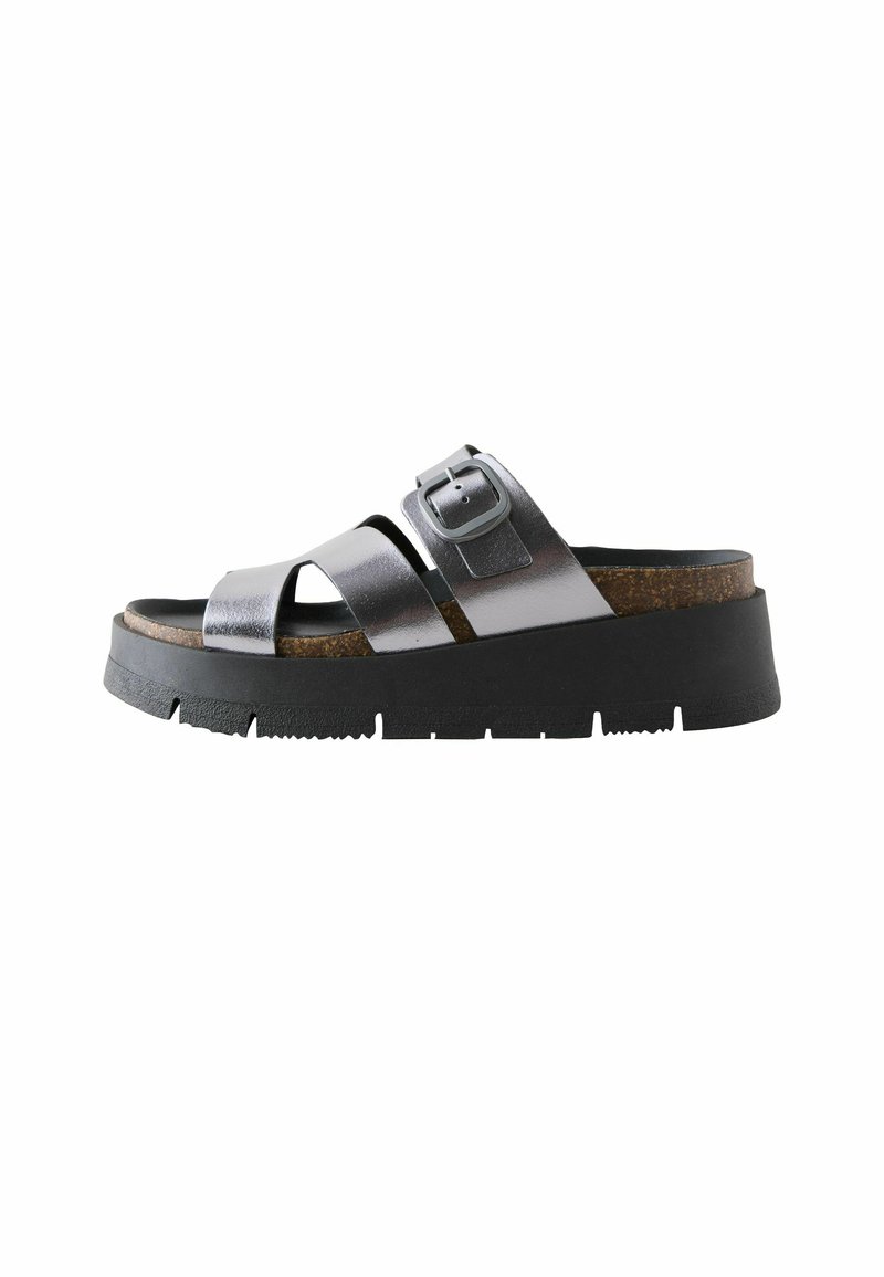 Sandales à plateforme noires avec des brides croisées en métal argenté, boucle ajustable, semelle en liège et semelle extérieure en caoutchouc texturé.