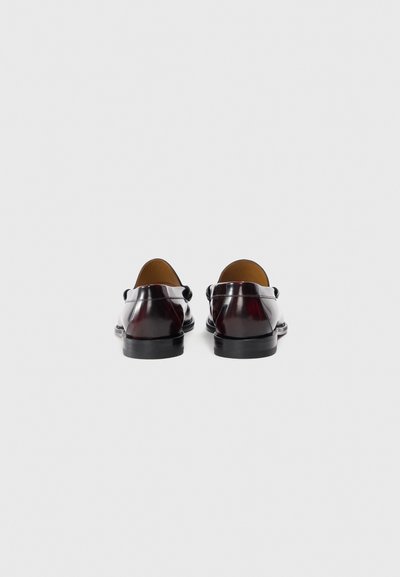 Leather loafers in a dark burgundy finish, featuring a smooth texture, rounded toe, and a low black heel, with minimal stitching details.