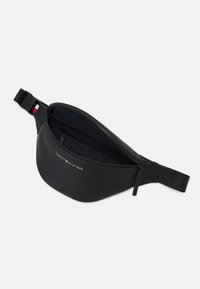 Zwarte heuptas met een gestructureerd oppervlak, voorzien van een ritsvak, een verstelbare band en een klein logo op de voorkant.