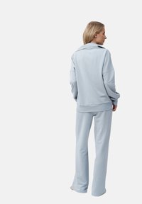 Lichtblauwe loungewear set bestaande uit een ontspannen long sleeves top met kraag en bijpassende taps toelopende broek, beide gemaakt van zacht katoen.