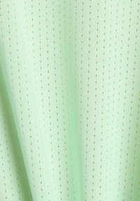 Tela perforada verde clara con pequeños agujeros distribuidos uniformemente y sutiles pliegues verticales.