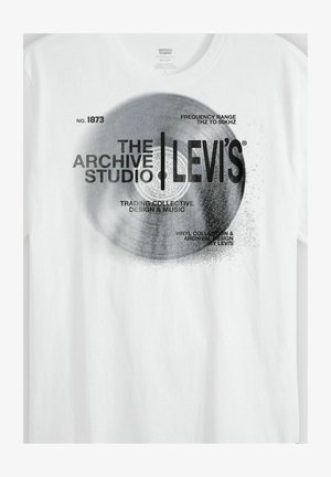 Valkoinen T-paita, jossa musta vinyylilevykuvio ja teksti: "The Archive Studio | Levi's", "Taajuusalue 7 Hz - 50 kHz" sekä suunnittelijan nimet.