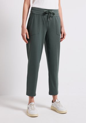 Groene sweatpants met een trekkoord in de taille, twee voorzakken en een taps toelopend ontwerp. Gemaakt van een zachte, gladde stof.