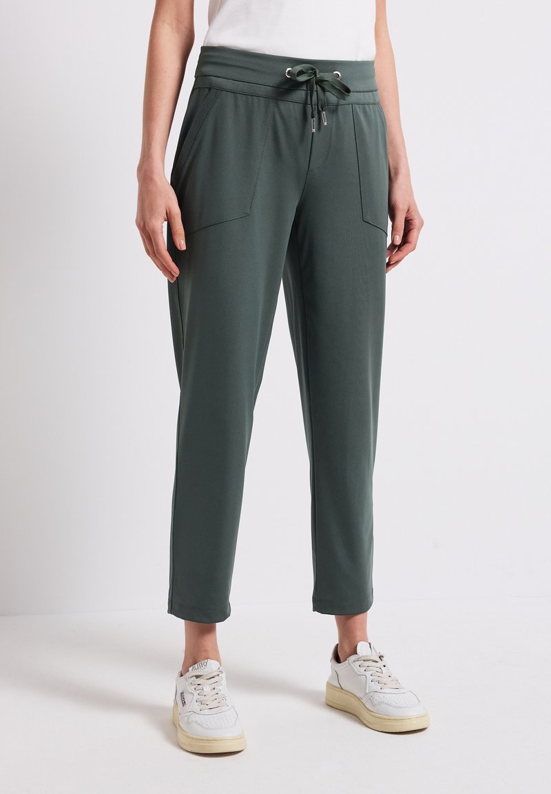 Zielone dresy z sznurkiem w pasie, dwoma przednimi kieszeniami i tapered leg design. Wykonane z miękkiego, gładkiego materiału.