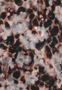 Ύφασμα με λεοπάρ σχέδιο που παρουσιάζει γκρί και μαύρες κηλίδες σε σκούρο φόντο, με υφή που περιλαμβάνει διακεκομμένες ασημένιες λεπτομέρειες και ελαφρώς διάφανο φινίρισμα.