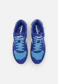 Blue and cyan athletic shoes with mesh fabric and suede overlays. Features textured accents and flat laces. Logo visible on insoles.