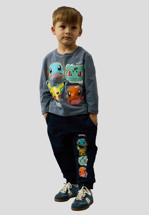 Blue long-sleeve shirt featuring colorful Pokémon graphics; navy pants with similar designs; casual sneakers with laces and blue accents.