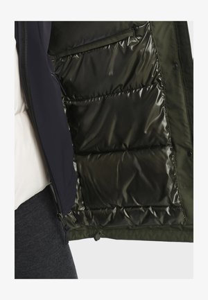 Doudoune en vert foncé avec une doublure intérieure brillante, dotée d'une fermeture éclair et de poches latérales. L'extérieur est texturé et doux.
