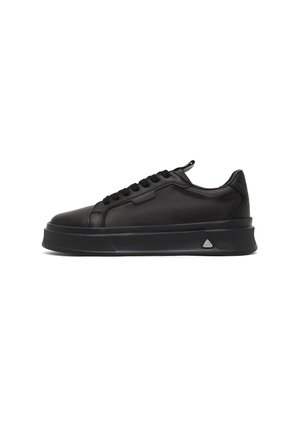Zapatilla negra de caña baja con suela gruesa, parte frontal con cordones y parte superior de cuero liso, vista de lado sobre fondo blanco.