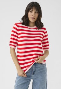 Rød og pink stribet kortærmet sweater med rund hals, parret med højdebukser i blå. Blød, strikket tekstur og afslappet pasform.