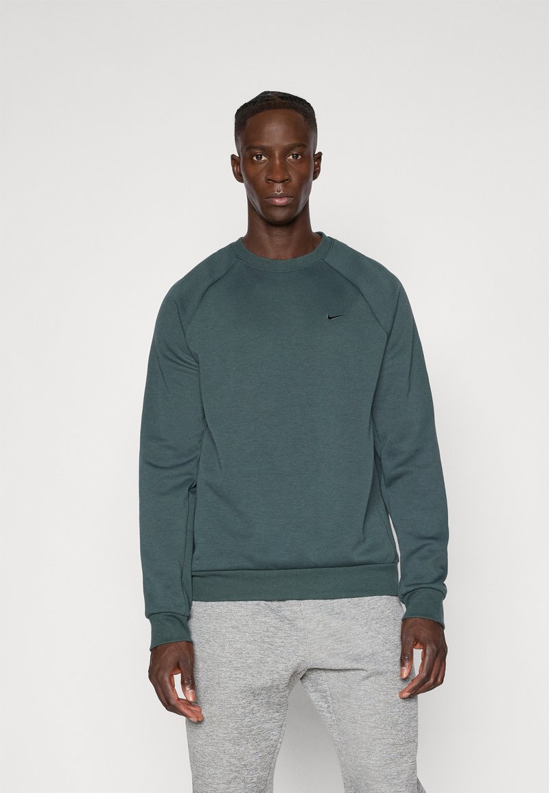 Sudadera verde de Nike con cuello redondo, puños y dobladillo acanalados, y un pequeño logo negro en el pecho. Tejido suave y texturizado.