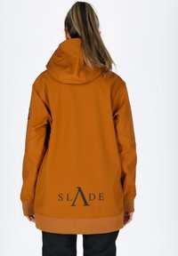 Giacca arancione con cappuccio, dal taglio rilassato, con un logo nero sulla schiena, polsini a costine e una texture liscia e opaca.