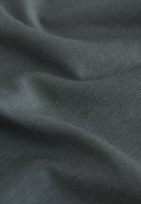 Sötétszürke szövet, sima, enyhén texturált felülettel, finom hajtásokkal és gyűrődésekkel, amelyek kiemelik a függesztési és anyagminőséget.