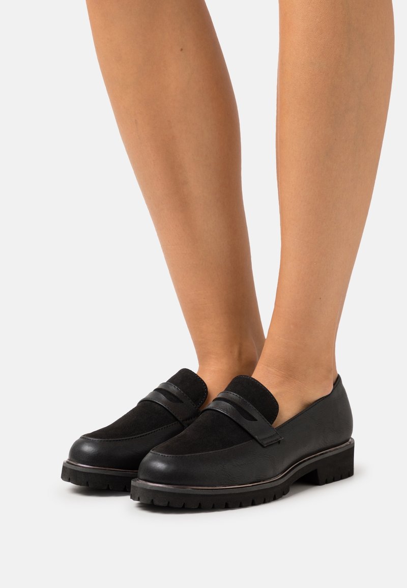 Mocassins noirs en cuir et daim, dotés d'un bout rond, de deux bandes d'accent et d'une semelle en caoutchouc texturée.