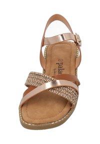 Bronzefarbene Riemchensandale mit strukturiertem Fußbett, Perlenakzenten am Riemen und einem verstellbaren Knöchelverschluss. Offenes Design für die Zehen.