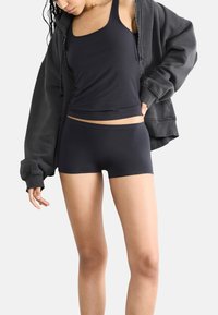 Top nero senza maniche e pantaloni corti realizzati in un morbido e elastico tessuto. Il top presenta un design aderente, mentre i pantaloni corti hanno un elastico in vita.
