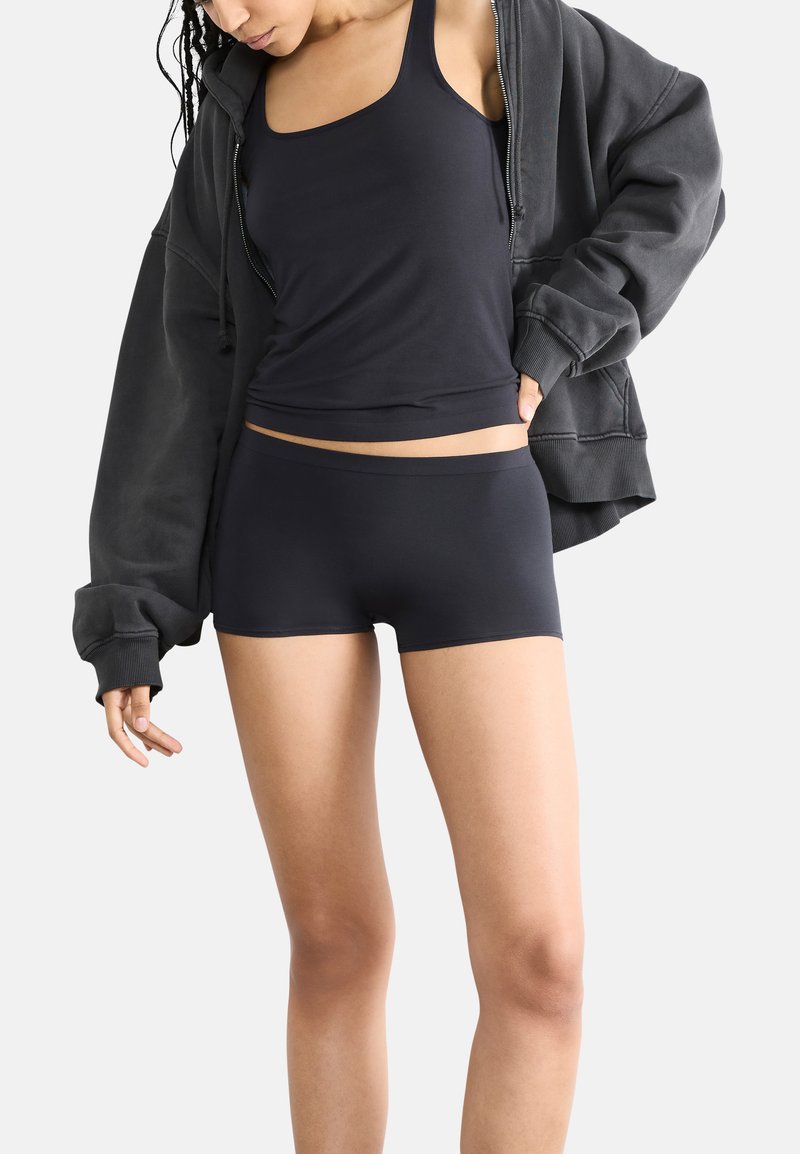 Top nero senza maniche e pantaloni corti realizzati in un morbido e elastico tessuto. Il top presenta un design aderente, mentre i pantaloni corti hanno un elastico in vita.