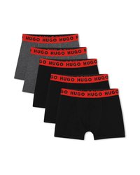 Πέντε ζευγάρια αντρικά μποξεράκια, τρία μαύρα και δύο σκουρόγρια, με κόκκινες μέσες που φέρουν τη λέξη «HUGO» σε μαύρο χρώμα.
