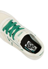 Vita Vans-sneakers med gröna snören, med en texturerad ovandel, en logotyp på tungan och en dämpad sula märkt "ComfyCush."
