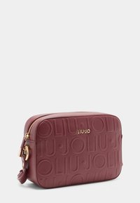 Beauty case in pelle testurizzata bordeaux con logo impresso, hardware dorato e chiusura a zip. Forma rettangolare compatta.