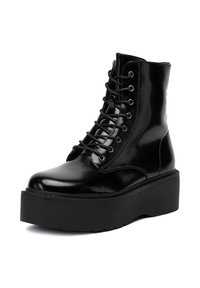 Czarne lakierowane buty wojskowe z zaokrąglonym noskiem, wysoką cholewką, sznurowanym przodem i grubą podeszwą. Posiadają wzmocnione szwy.