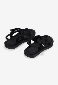 Black sandals featuring a strap design, textured footbed, and thick black sole. Materials include durable fabric and rubber.