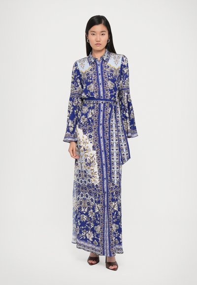 Robe longue à motifs bleus avec des designs floraux et géométriques ; présente un col, une taille ceinturée et des manches fluides.