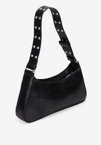Bolso de hombro de cuero negro con forma curvada. Presenta una correa con tachuelas, detalles de hardware en plata y un acabado texturizado.