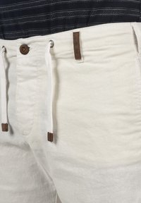 Witte linnen shorts met een drawstring taille, voorzien van bruine leren accenten en een knoopsluiting. Textuur, lichtgewicht stof.