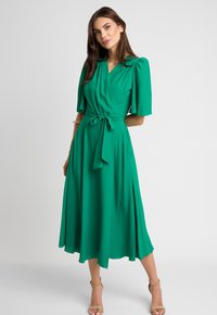 Zielona sukienka wrap z gładkiego materiału, z krótkimi bufkami, paskiem do zawiązania w talii oraz zwiewną, w kształcie litery A spódnicą.