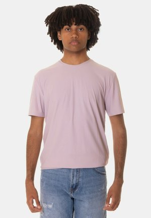 T-shirt viola chiaro a maniche corte con scollatura rotonda, realizzato in tessuto morbido, abbinato a jeans azzurri strappati.