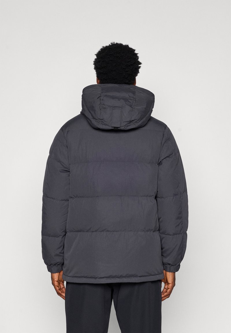 Grey padded jacket with a hood, featuring a quilted design, long sleeves, and elastic cuffs. The texture appears smooth and insulated.