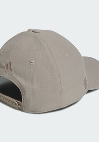 Casquette beige avec un design structuré, un textile lisse, une sangle réglable et trois accents rayés sur le côté.