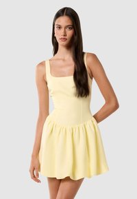 Gelbes Skaterkleid mit quadratischem Ausschnitt und breiten Trägern, das einen ausgestellten Saum aus weichem Stoff mit glatter Textur hat.