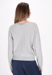 Lichtgrijze gebreide trui met een wijde halslijn, lange mouwen en een getailleerde taille. Heeft een gladde textuur en een relaxte pasvorm.