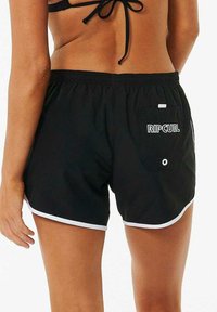 Shorts de bain noirs en matériau léger, avec des bordures blanches, une taille élastique et une poche arrière avec un logo.
