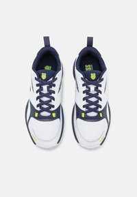 Scarpe sportive bianche e blu navy con tomaia in mesh testurizzato, suola in gomma, punta tonda e accenti verdi a contrasto sui lacci e sul logo.