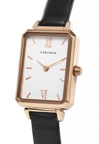 Montre rectangulaire avec un cadran blanc, des accents dorés, des marqueurs en or rose et un bracelet en cuir noir texturé. Présente une couronne sur le côté.