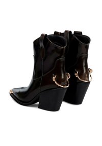 Botas de tobillo de charol negro con punta afilada, tacón grueso negro y detalles de hardware dorado en la parte trasera.