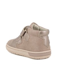 Stivaletto in suede beige con dettagli metallici, cinturino in Velcro, punta rotonda e lati testurizzati. Presenta una suola in gomma e colletto imbottito.
