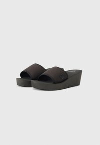 Sandale negre cu toc wedge, cu parte superioară din țesătură, vârf deschis și talpă platformă. Prezintă un logo ridicat pe lateral și o textură netedă.