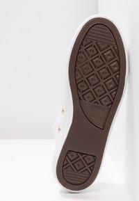 Semelle blanche de basket avec bande de roulement en caoutchouc brun présentant un motif en losange et marquage Converse All Star visible.