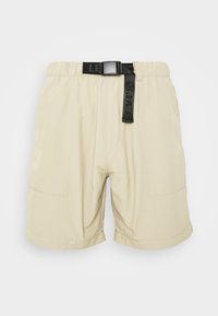 Beige šortky s elastickým pasem, černým nastavitelným pásem a dvěma bočními kapsami. Tkanina vypadá měkce s mírným leskem.