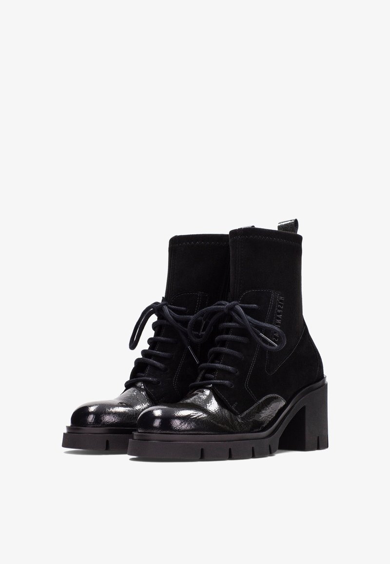 Botines negros con una combinación de materiales de ante y charol, puntera redonda, diseño de cordones y un tacón grueso.