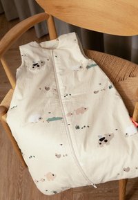 Crème-kleurige slaapzak met dierenillustraties in zachte pastelkleuren. Ritssluiting in het midden, soepele stof met een lichte textuur.