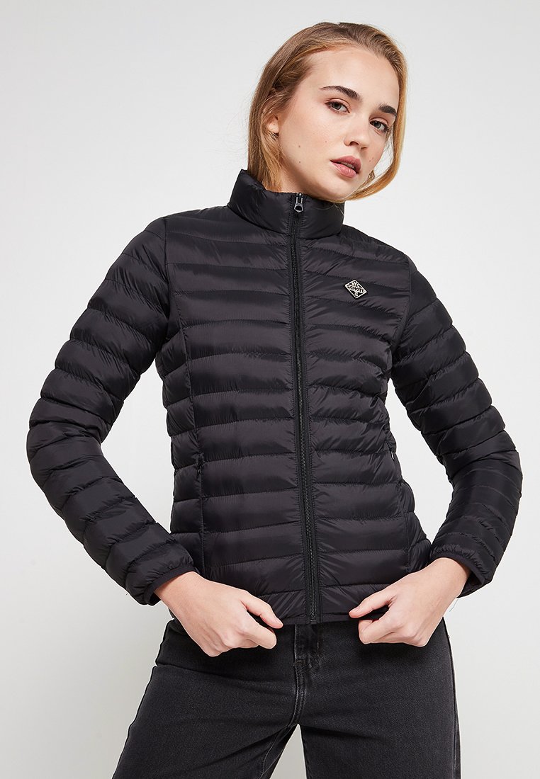 Veste en duvet noire avec des coutures horizontales, col montant et fermeture éclair à l'avant. Présente un petit logo sur la poitrine gauche. Texture lisse.