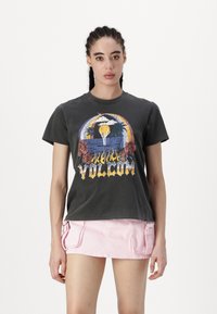 Camiseta gráfica gris con estampado colorido de flores y un volcán, de manga corta y cuello redondo, combinada con una mini falda rosa claro con bolsillos.